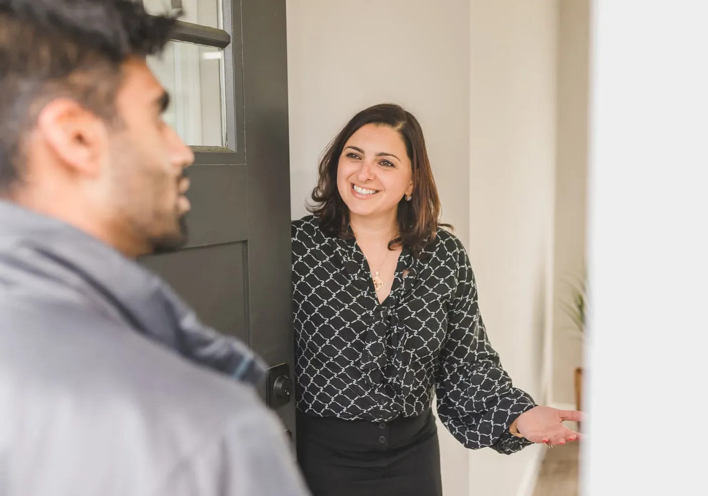 Professionnelle accueillant un visiteur à la porte d’un logement