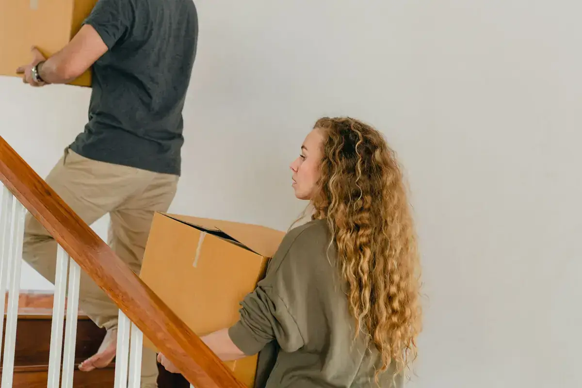 Deux personnes transportant des cartons dans un escalier