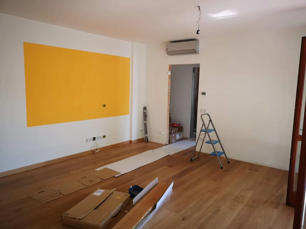 Pièce en rénovation avec escabeau, parquet et mur jaune
