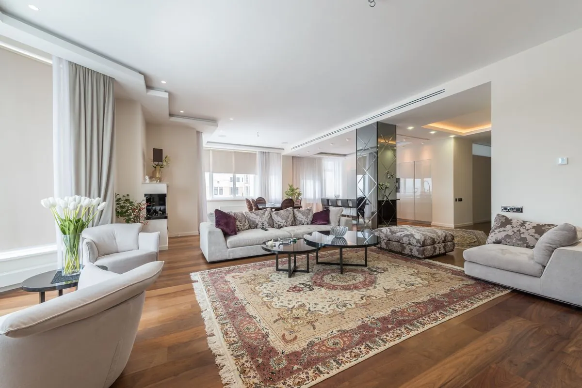 Salon lumineux avec canapés, fauteuils et grandes fenêtres