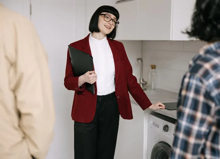 Agent immobilier faisant visiter une cuisine moderne à deux personnes