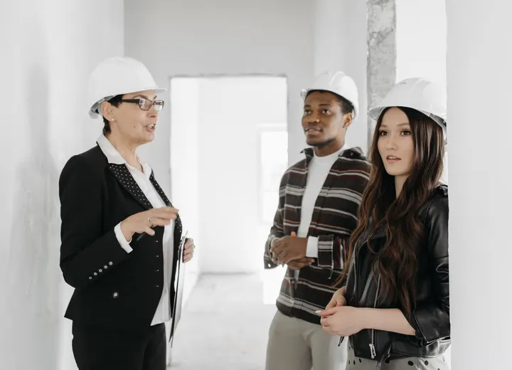 Clients et professionnelle visitant un appartement en chantier avec des casques