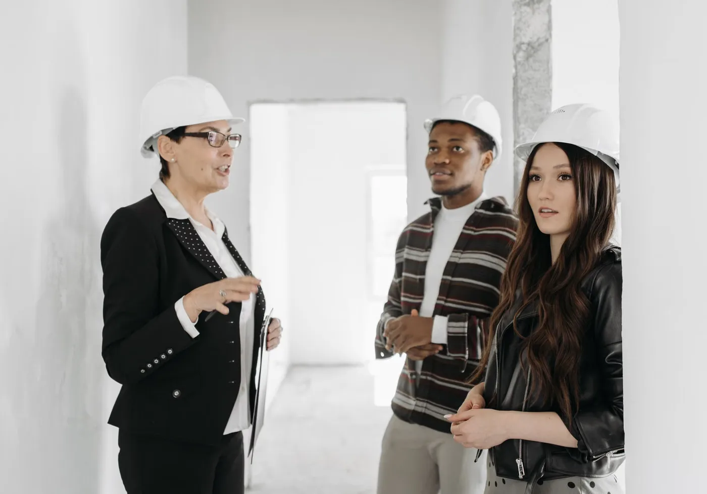 Clients et professionnelle visitant un appartement en chantier avec des casques